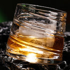 Swirl pattern spinning whiskey glass tilted mid-spin